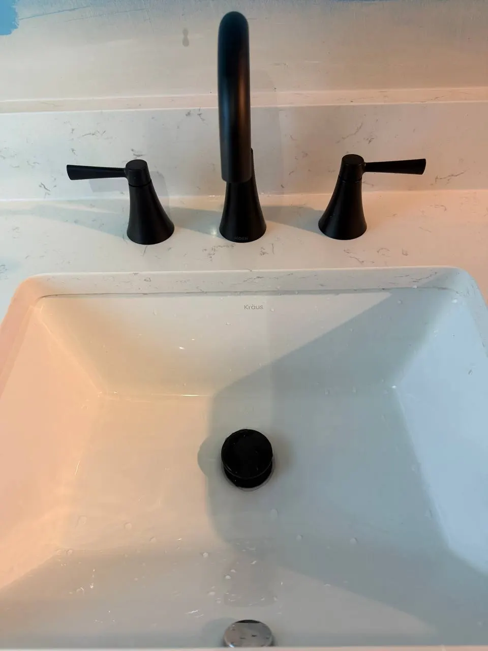 Finished vanity with a black widespread faucet and matching drain in a white undermount sink