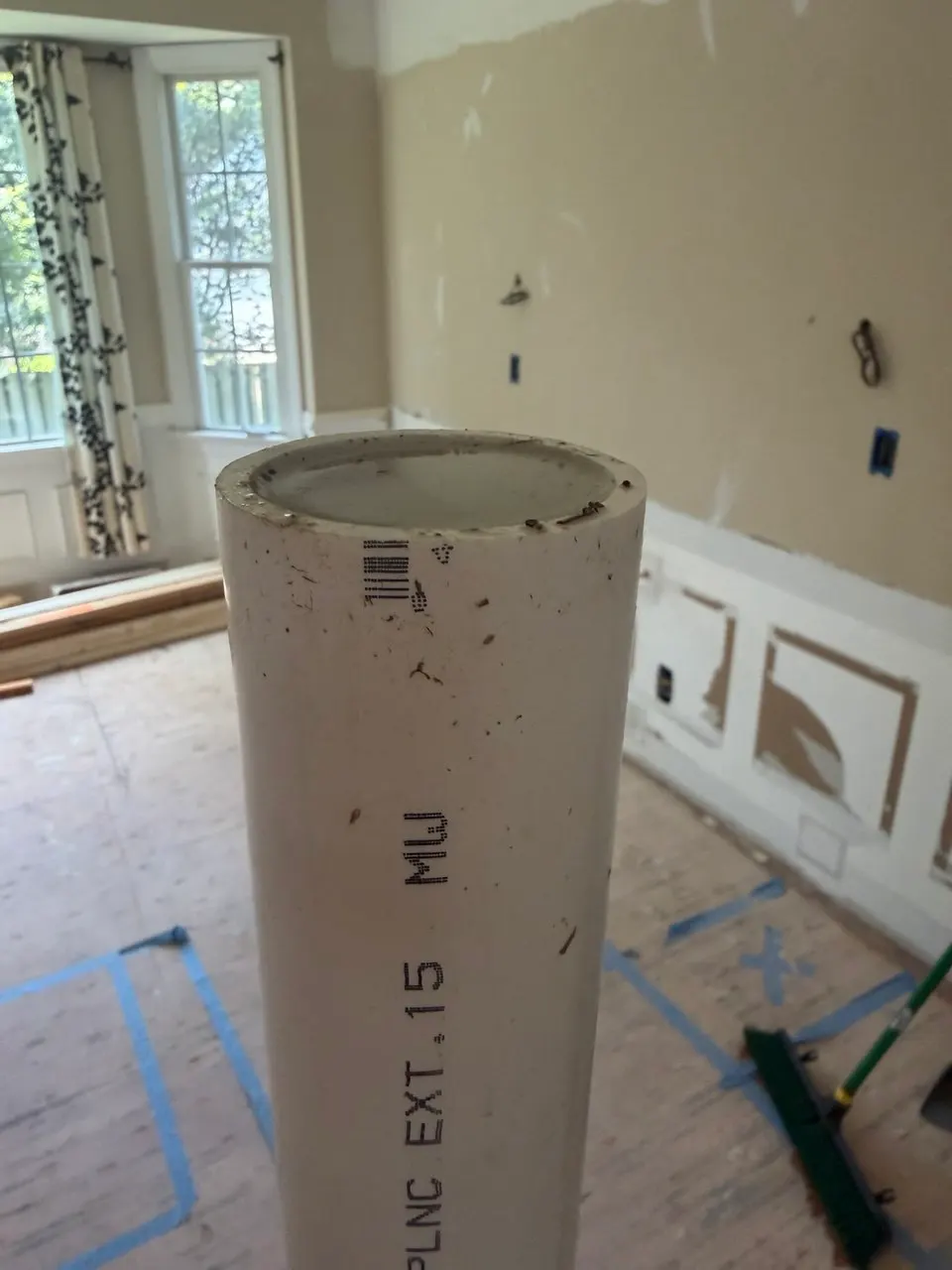 Close-up of the open top of the kitchen island drain riser in the gutted kitchen