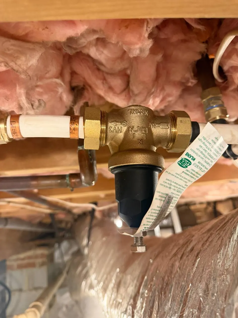 New brass pressure-reducing valve with union connections, joined to the supply piping in the crawl space