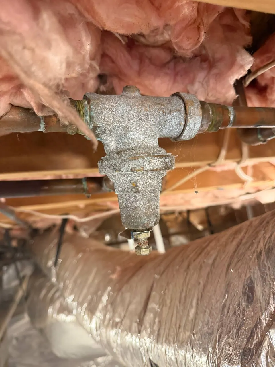 The failed pressure-reducing valve before replacement, heavily corroded on the copper supply line